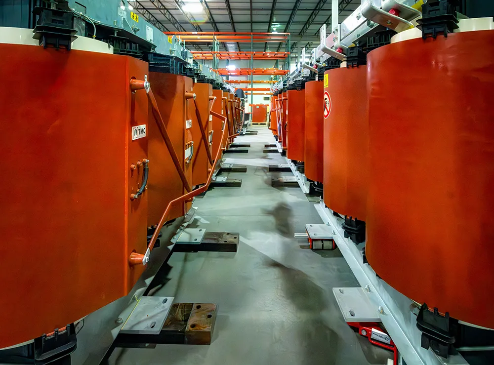 The TMC production plant features a row of precision-built cast resin transformers undergoing testing and final quality inspection.